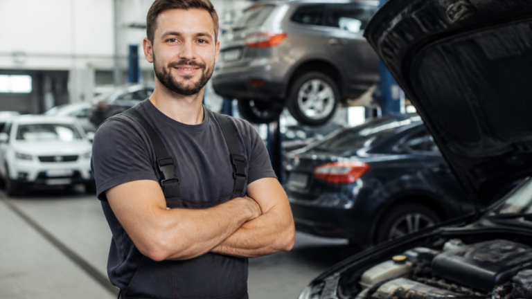 Mécanicien travaillant sur différentes marques de voitures dans un garage multimarque
