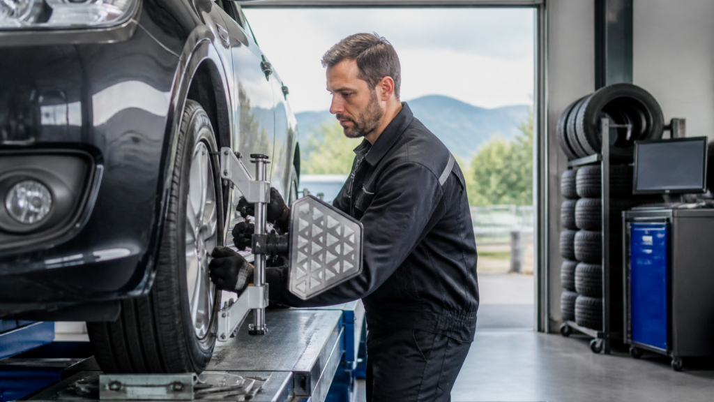 Garagiste contrôlant l'alignement des roues d'une voiture dans un garage auto français