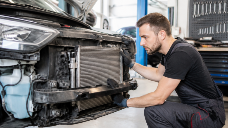 Garagiste inspectant un condenseur de climatisation automobile dans un garage