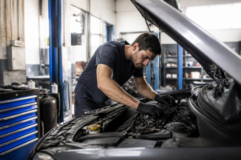 Garagiste inspectant le moteur d'une voiture dans un garage automobile à Nurieux