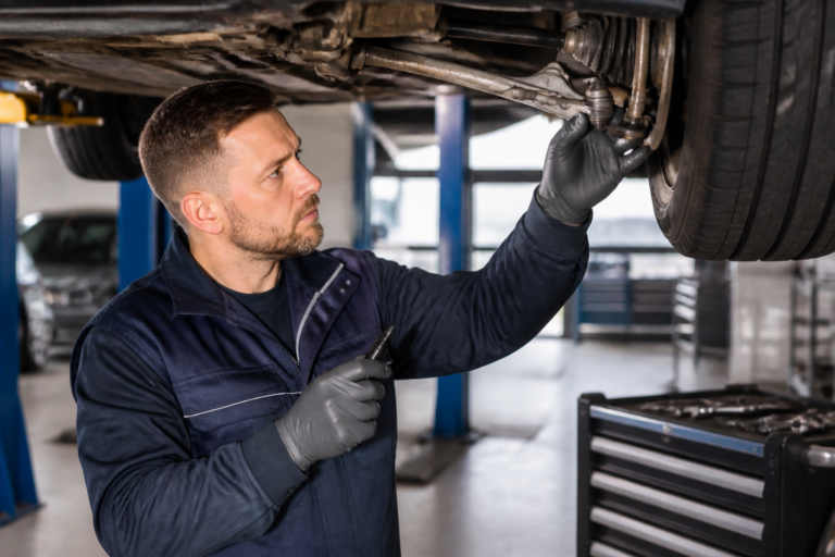 Mécanicien vérifiant la rotule de direction d'une voiture dans un garage automobile