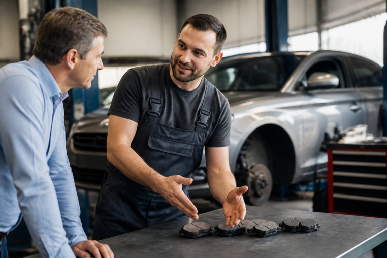 Garagiste expliquant les plaquettes de frein à un client dans un garage automobile moderne